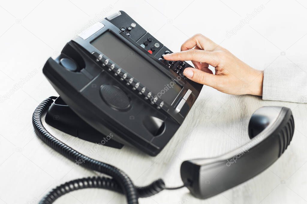 business and communications. Using voip phone in the office, close up of hand with receiver. Conference call, contact us or hotline. IP telephony, Telemarketing. Help desk or call centre