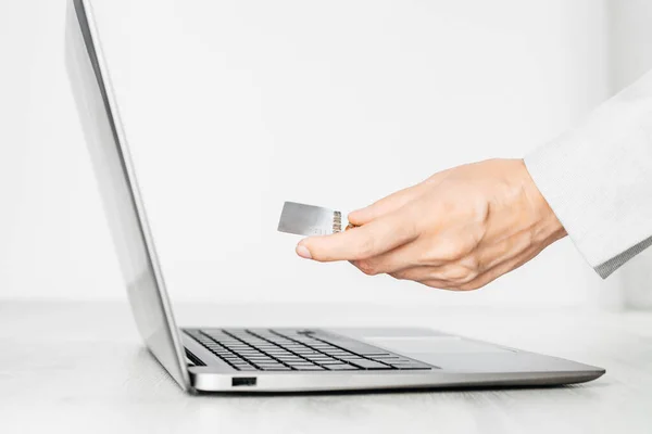 Laptop side view. female hand with a credit card. Online shopping or banking and paying for services. Monochrome. Internet data safety.