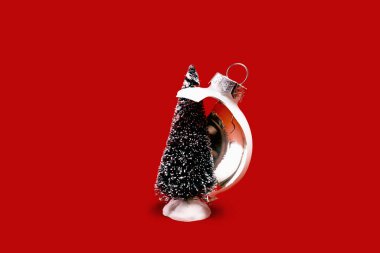 White broken glass bauble on red Christmas background with Christmas tree. Winter holiday season depression and stress, mental health problems. Shattered dreams. Copy space clipart