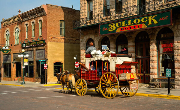 DEADWOOD, SD, USA - SEPTEMBER 15, 2020: An old-fashioned stagecoach carries tourists past the old Bullock Hotel on Main St. in this Black Hills gold rush town, famous for outlaws and entrepreneurs alike.