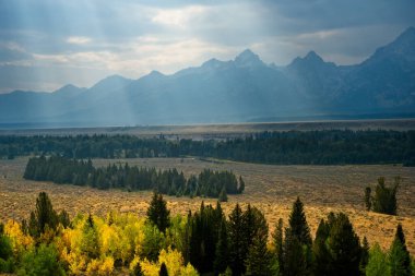 Öğleden sonra Büyük Tetonlar 'ın üzerindeki sislerin arasından süzülen güneş ışınları.