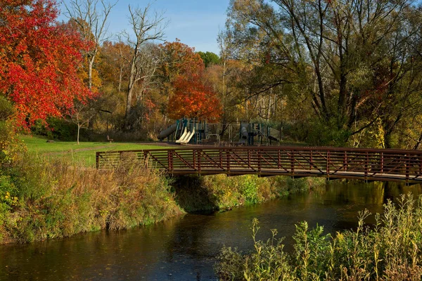 秋には公園遊技場前の小川を渡る絵のように美しい歩道橋 — ストック写真