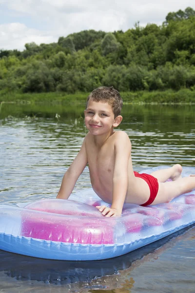 Été sur le garçon de la rivière est assis sur un matelas gonflable sur la rivière . — Photo