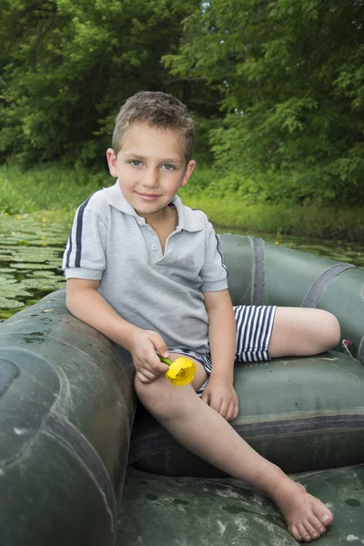 In estate sul fiume un ragazzino che si siede in una barca di gomma — Foto Stock