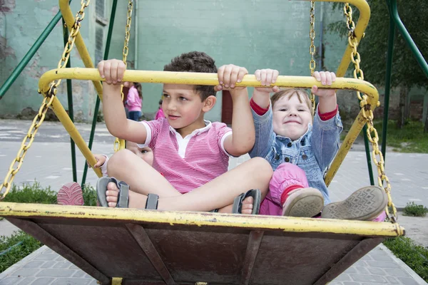 En été, les enfants au terrain de jeux sur une balançoire . — Photo