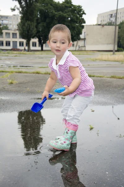 Im Sommer spielt ein kleines Mädchen mit einer Schaufel in der Nähe des Stadions. — Stockfoto