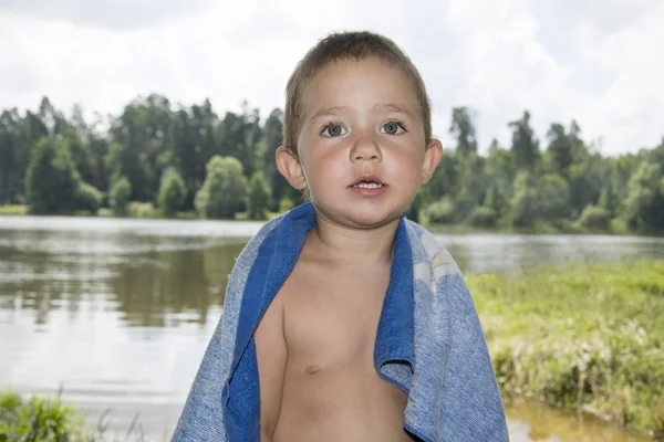 In the summer on the banks of the river there is a small child i — Stock Photo, Image