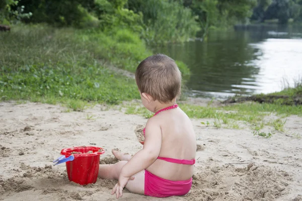 In the summer on the banks of the river a little  baby dig sand — Stock Photo, Image