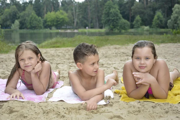 En verano, en la playa cerca del río hay niños en la arena . —  Fotos de Stock