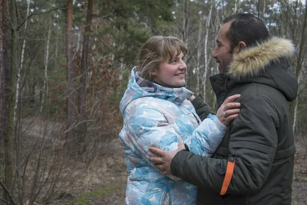 秋の終わりに森の中で女の子は笑顔で男を抱きしめる — ストック写真