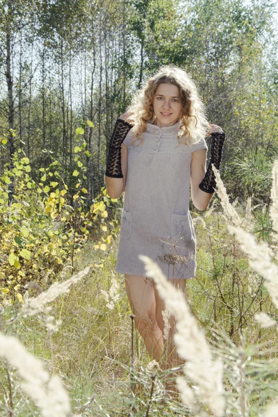 En el bosque de otoño en un claro chica rizada en la hierba alta en el —  Fotos de Stock