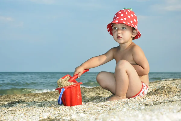 Menina no verão no mar faz uma casa de areia . — Fotografia de Stock