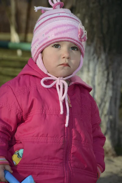 Little upset girl standing alone on a street in the spring. — Stock Photo, Image