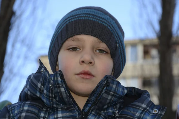 Piccolo ragazzo riccio dagli occhi verdi si trova sulla strada . — Foto Stock