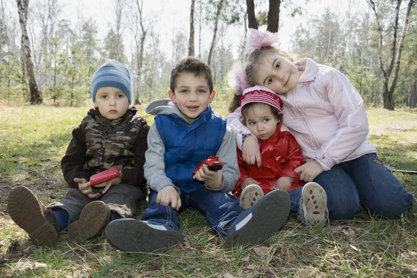 Los niños se sientan en la hierba en el bosque en la primavera . — Foto de Stock