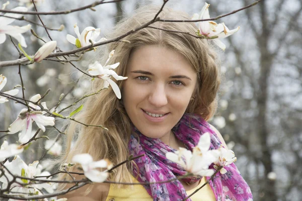 Meisje permanent in de bloemen van Magnolia. — Stockfoto