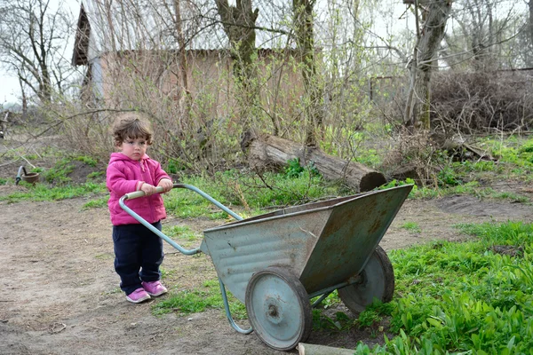 En la primavera de niña rural pequeña lleva una carretilla . — Foto de Stock