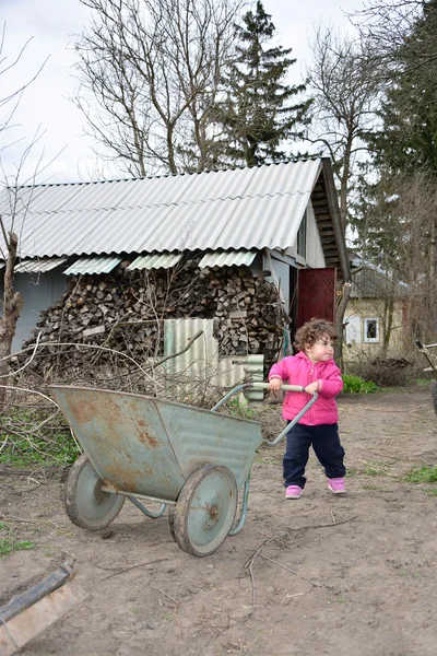 En la primavera de niña rural pequeña lleva una carretilla . — Foto de Stock