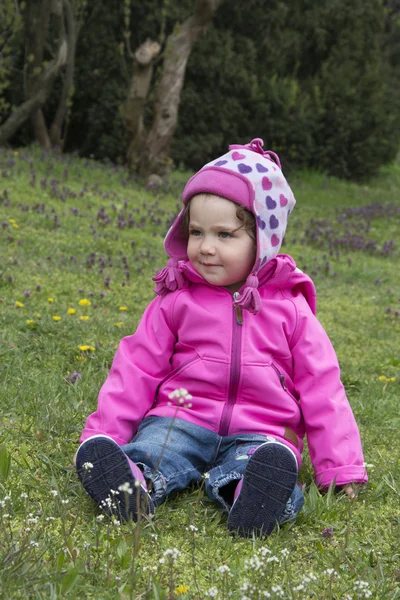 En la primavera de una niña sentada en un prado en la hierba . — Foto de Stock