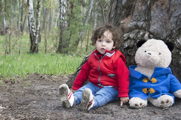 Primavera en el bosque niña jugando con un oso de juguete . — Foto de Stock