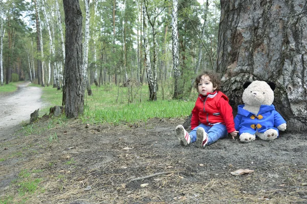 Spring i skogen lite flicka som leker med en leksak Björn. — Stockfoto