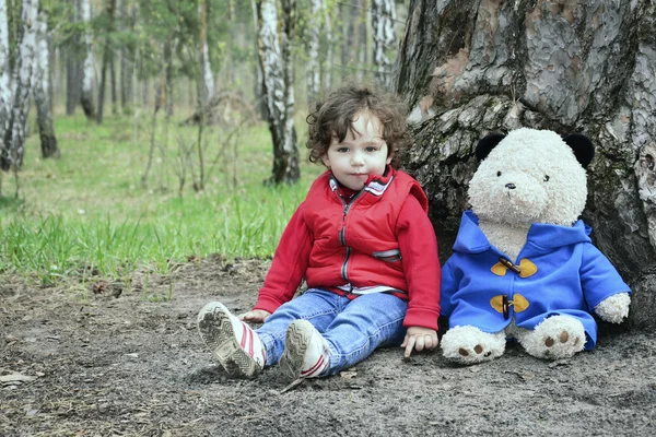 Άνοιξη στο δάσος κοριτσάκι που παίζει με ένα παιχνίδι αρκούδα. — Φωτογραφία Αρχείου