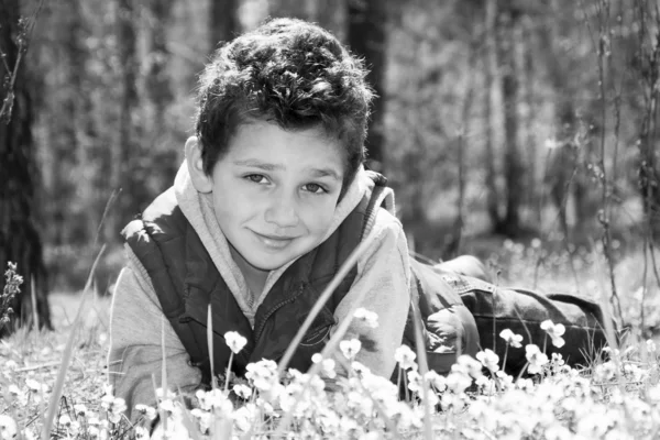 Voorjaar in het bos in de weide liggen een gelukkige jongen. Stockfoto