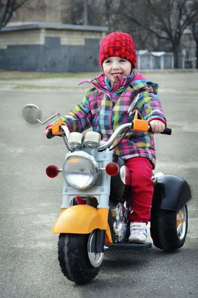 In het voorjaar een klein meisje rijden op een motorfiets. — Stockfoto