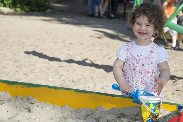 Im Sommer auf dem Spielplatz spielt kleines Mädchen im Sandkasten — Stockfoto