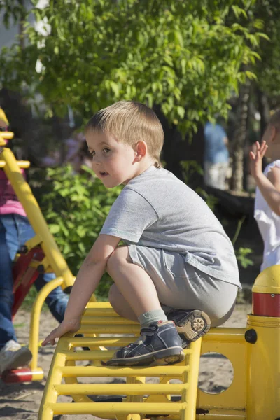 En été, un petit garçon joue sur l'aire de jeux . — Photo