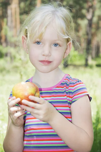 No verão na floresta a menina come uma maçã . — Fotografia de Stock