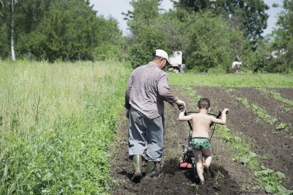 Im Frühling pflügen Vater und Sohn den Boden im Garten — Stockfoto