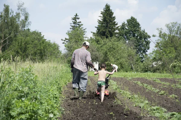 In the spring of father and son plowing the ground in the garden — Stock Photo, Image