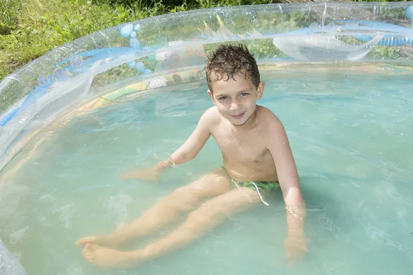 No verão, o jardim é banhado em um menino inflável da piscina . — Fotografia de Stock