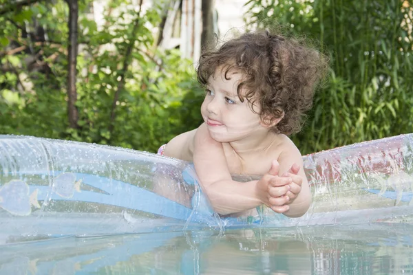 In de zomer de tuin baadt in een opblaasbaar zwembad meisje. — Stockfoto