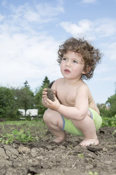 In de zomer, een beetje krullend meisje in korte broek werken in de gard — Stockfoto