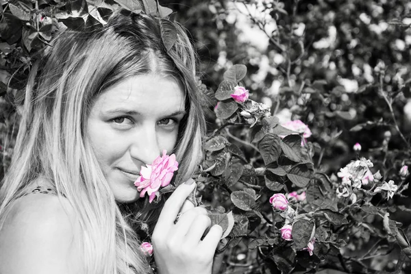Zomer in de tuin vrouw stond in de buurt van een rozenstruik. Close-up. — Stockfoto
