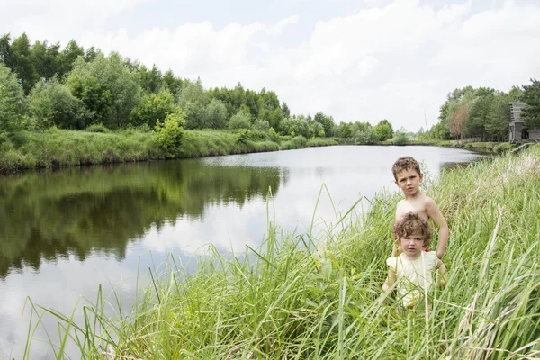 Latem nad brzegiem jeziora są małych wiejskich dzieci kręcone w — Zdjęcie stockowe