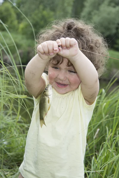 In the summer of little curly girl in awe of carp caught. — Stock Photo, Image