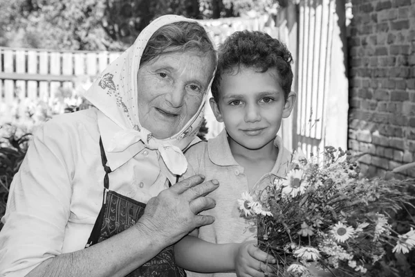 Lato w ogrodzie na słoneczny dzień babci z wnukiem, trzyma bukiet kwiatów. — Zdjęcie stockowe