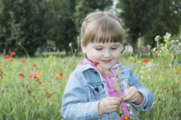 Im Sommer ist der Park ein kleines Mädchen im Blumenbeet. — Stockfoto