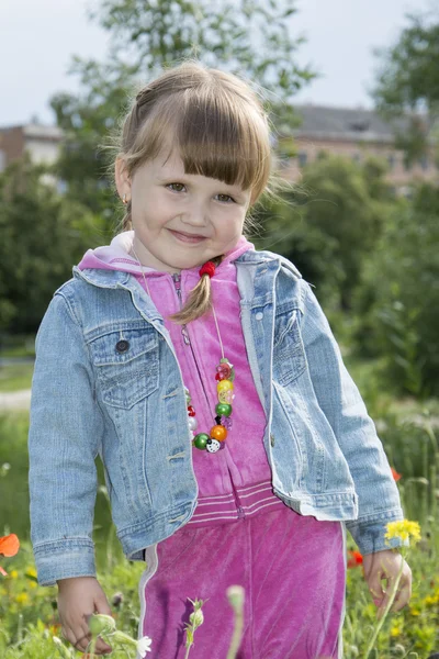 Im Sommer ist der Park ein kleines Mädchen im Blumenbeet. — Stockfoto
