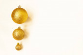 Tři zlaté vánoční míčky různých velikostí jsou zobrazeny v řadě jako okraj na bílém pozadí. Kopírovat prostor.