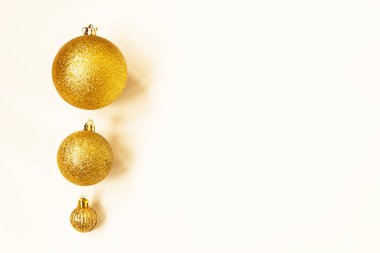Farklı boyutlarda üç altın Noel topu arka planda bir kenar olarak sergileniyor. Boşluğu kopyala.