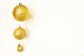 Tři zlaté vánoční míčky různých velikostí jsou zobrazeny v řadě jako okraj na bílém pozadí. Kopírovat prostor