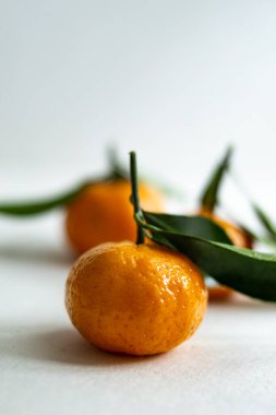 Hafif arka planda yaprakları olan üç olgun mandalina. Boşluğu kopyala