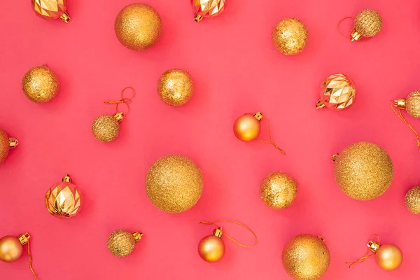 Gold glitter. Christmas balls of different sizes on a pink background pattern. Flat lay, top view.