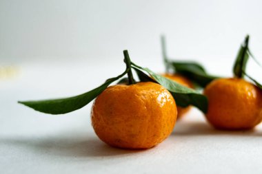 Hafif arka planda yaprakları olan üç olgun mandalina. Boşluğu kopyala.