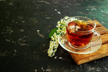Siyah arka planda kiraz çiçekli bir fincan çiçek çayı. Boşluğu kopyala.