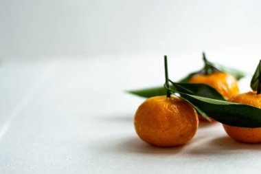 Hafif arka planda yaprakları olan üç olgun mandalina. Boşluğu kopyala